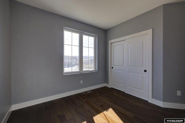 unfurnished bedroom with dark hardwood / wood-style flooring and a closet