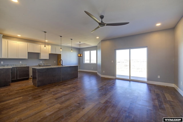 kitchen with sink, dark wood-type flooring, an island with sink, and white cabinets