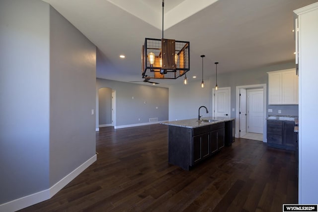 kitchen with dark hardwood / wood-style floors, pendant lighting, white cabinetry, an island with sink, and sink