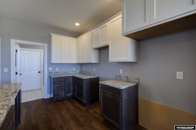 kitchen featuring light stone counters, dark brown cabinets, dark hardwood / wood-style floors, and white cabinets