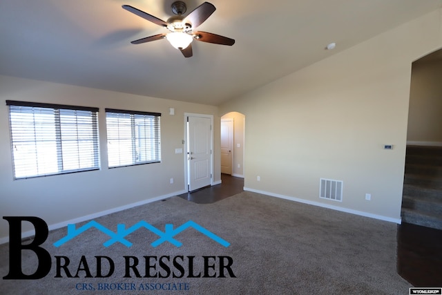 interior space featuring dark carpet, vaulted ceiling, and ceiling fan