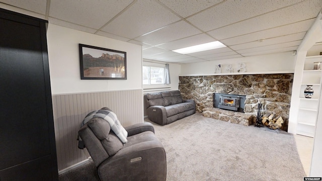 living room with a drop ceiling and a wood stove