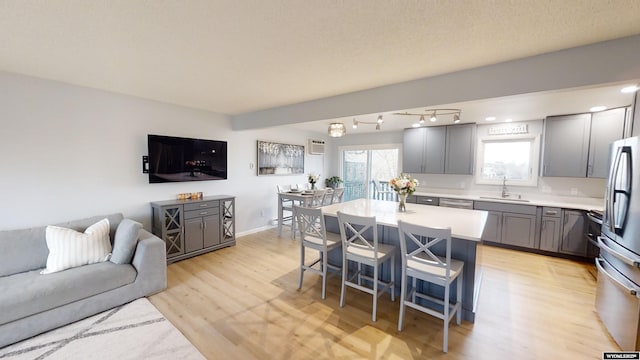 kitchen with a breakfast bar, sink, a center island, light hardwood / wood-style flooring, and stainless steel appliances