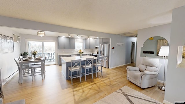 interior space featuring a kitchen bar, gray cabinetry, stainless steel fridge with ice dispenser, a kitchen island, and light hardwood / wood-style floors