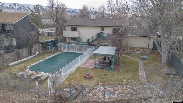 view of swimming pool with a yard, a deck with mountain view, and a fire pit