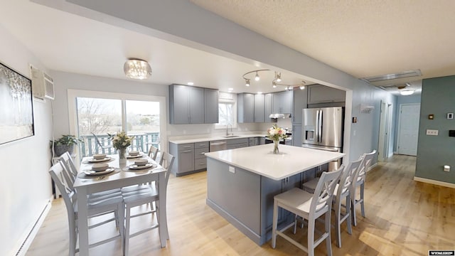 kitchen featuring gray cabinets, appliances with stainless steel finishes, sink, a center island, and light wood-type flooring