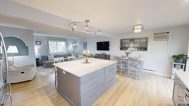 kitchen featuring light hardwood / wood-style flooring, a wall unit AC, a center island, and gray cabinets