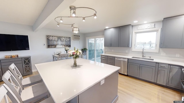 kitchen featuring a kitchen island, sink, stainless steel dishwasher, and gray cabinetry