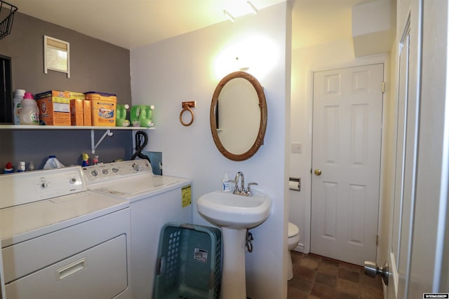 bathroom with sink, washing machine and clothes dryer, and toilet