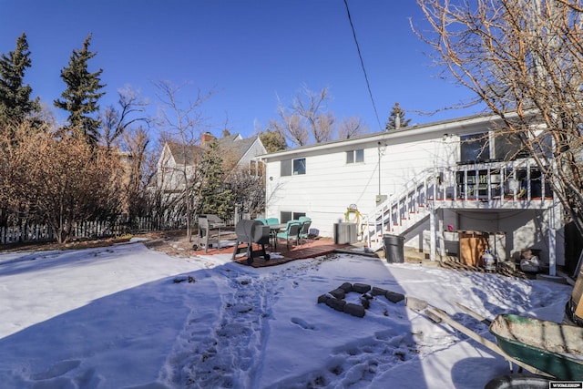 snow covered back of property with a deck