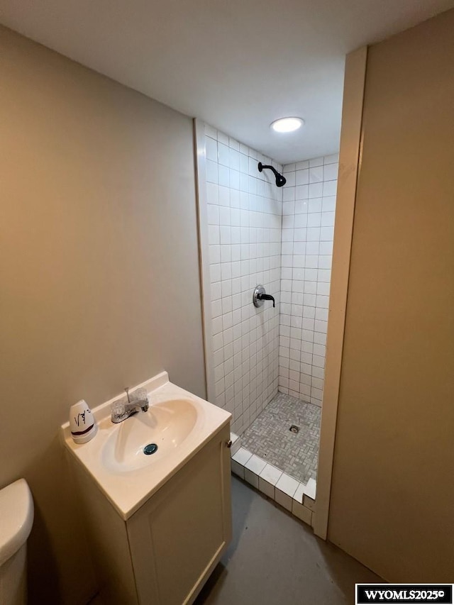 bathroom featuring tiled shower, vanity, and toilet