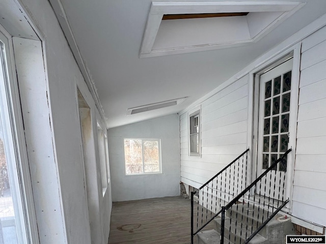 interior space with vaulted ceiling, hardwood / wood-style floors, and wooden walls