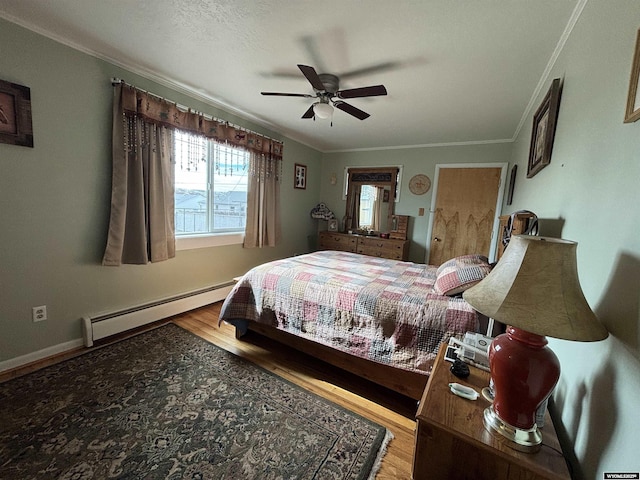 bedroom with crown molding, hardwood / wood-style floors, and a baseboard heating unit