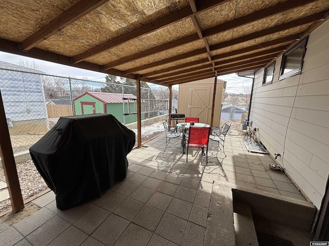 view of patio / terrace with a storage shed and a grill