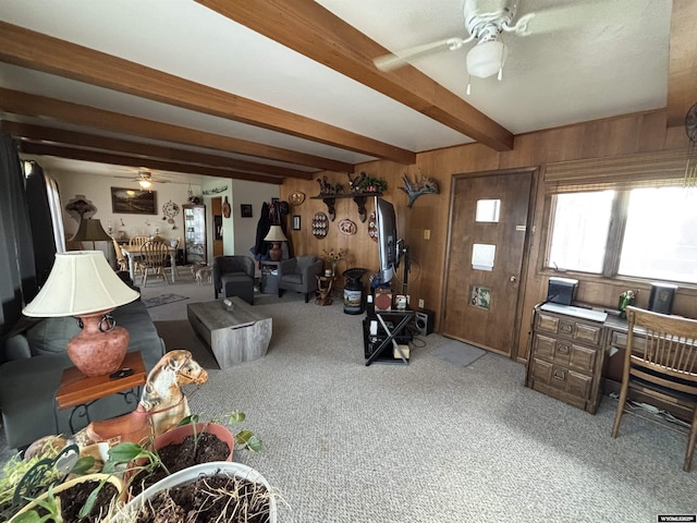 interior space featuring beamed ceiling, wooden walls, carpet flooring, and ceiling fan