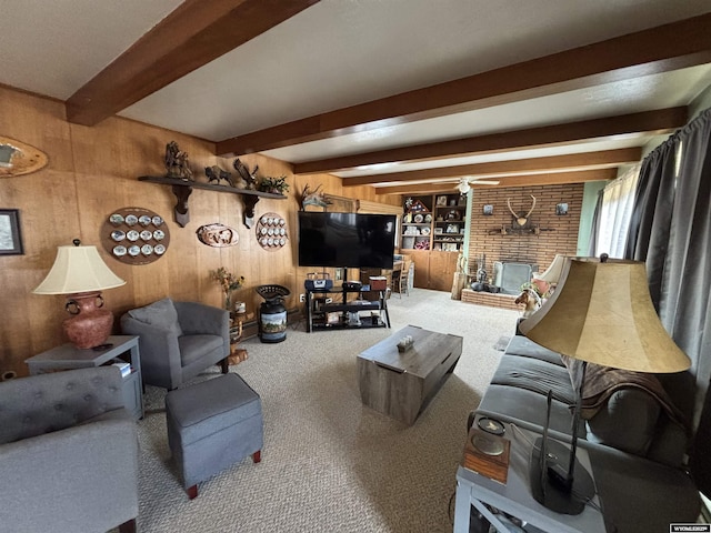 carpeted living room featuring ceiling fan, a fireplace, beamed ceiling, and wood walls