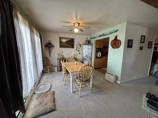 carpeted dining area with ceiling fan