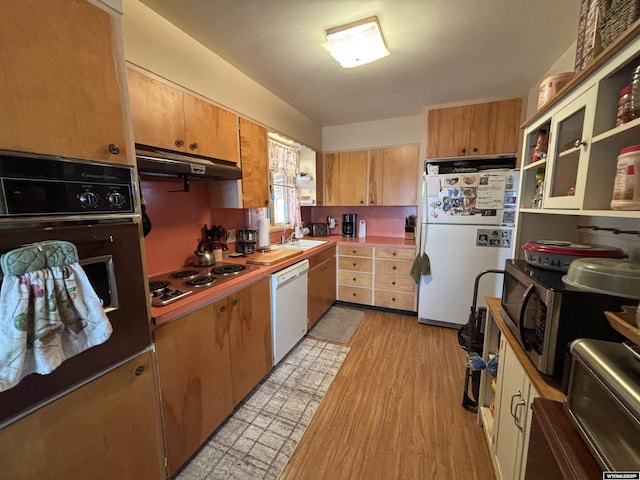 kitchen with light wood-type flooring, sink, and white appliances