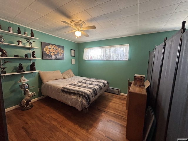 bedroom with dark wood-type flooring, ceiling fan, and a baseboard heating unit