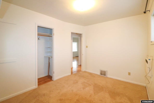 unfurnished bedroom featuring light colored carpet and a closet