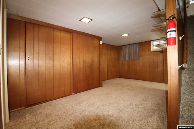 basement with light carpet and wood walls