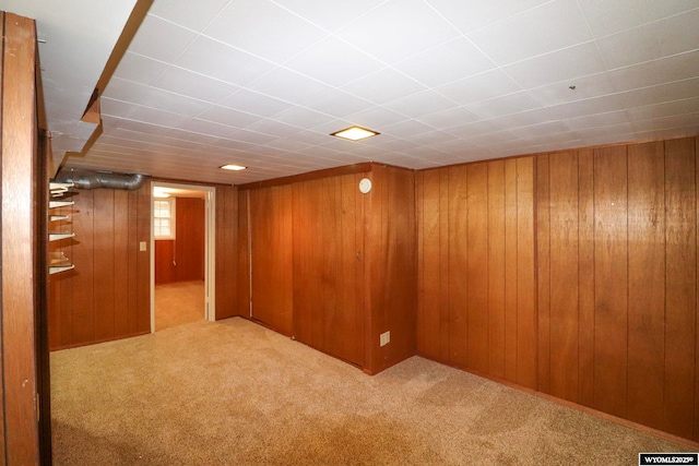 basement featuring light colored carpet and wood walls