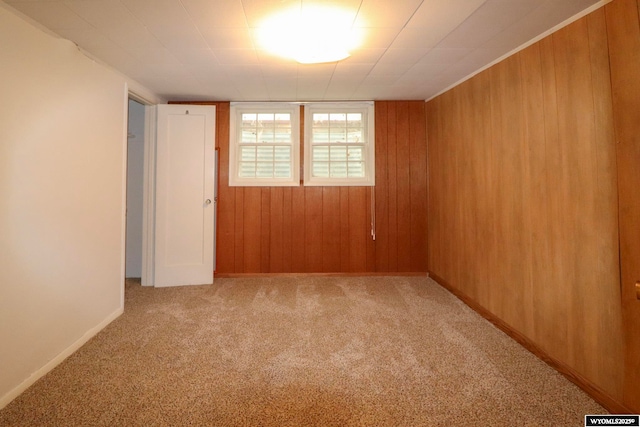 carpeted spare room featuring wood walls