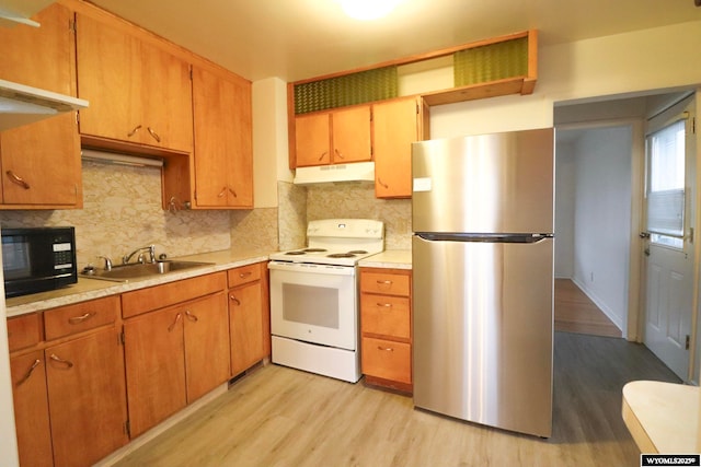 kitchen with sink, stainless steel refrigerator, white range with electric cooktop, decorative backsplash, and light wood-type flooring