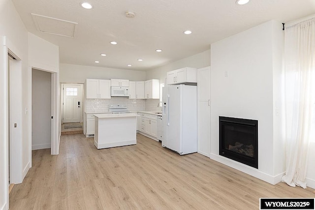 kitchen with backsplash, white cabinets, a center island, white appliances, and light hardwood / wood-style flooring