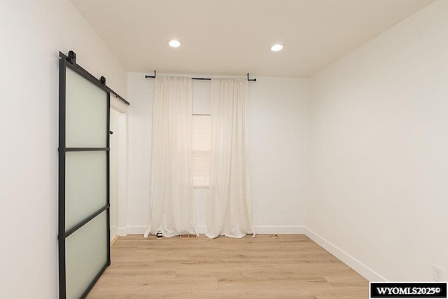 spare room featuring a barn door and light wood-type flooring