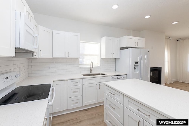 kitchen with sink, white appliances, white cabinetry, backsplash, and light wood-type flooring