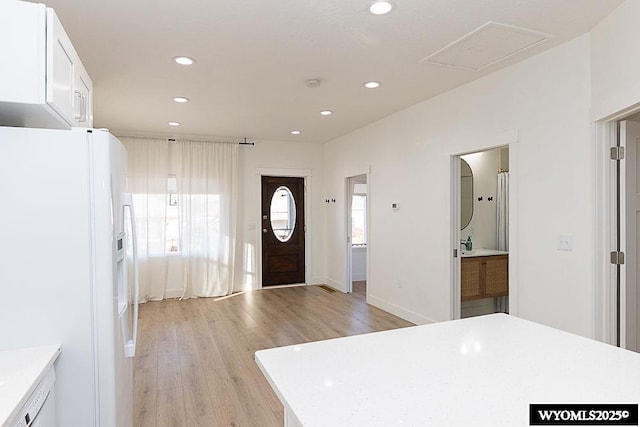 kitchen with white fridge with ice dispenser, white cabinets, and light hardwood / wood-style floors