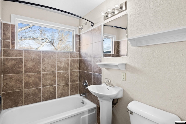 bathroom featuring toilet and tiled shower / bath combo