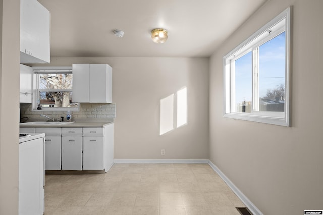 kitchen featuring backsplash, plenty of natural light, white electric range oven, and white cabinets