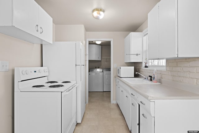 kitchen with independent washer and dryer, sink, white cabinets, and white appliances