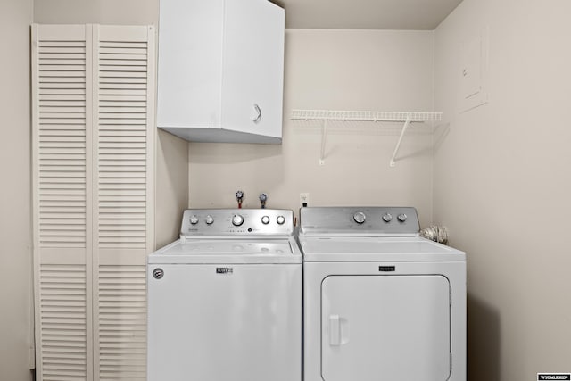 clothes washing area with cabinets and separate washer and dryer