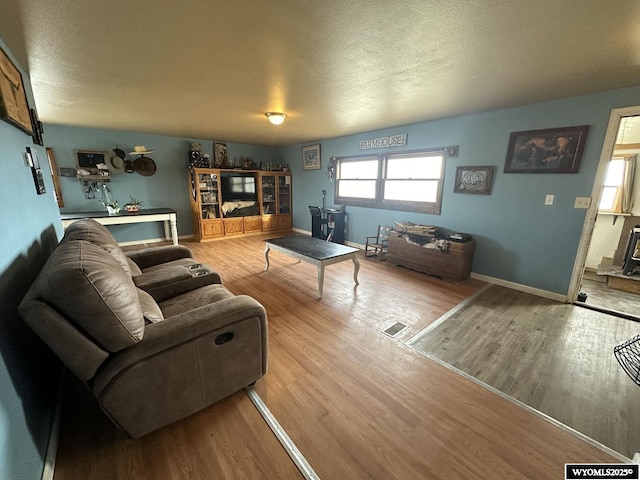 living room featuring a textured ceiling and light hardwood / wood-style floors