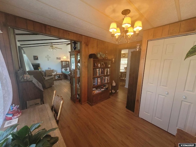 dining space with hardwood / wood-style flooring, wooden walls, and an inviting chandelier