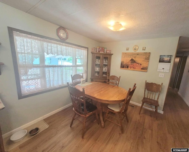 dining space with hardwood / wood-style flooring and a textured ceiling