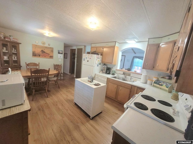 kitchen featuring sink, white appliances, light hardwood / wood-style flooring, and a textured ceiling