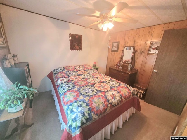 bedroom featuring wooden walls, ceiling fan, and carpet flooring