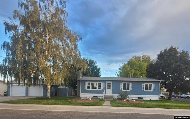 ranch-style home featuring a garage, a front lawn, and a storage shed