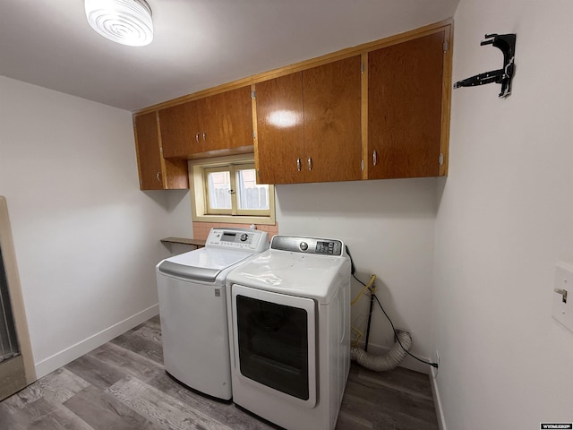 clothes washing area with independent washer and dryer, light hardwood / wood-style flooring, and cabinets