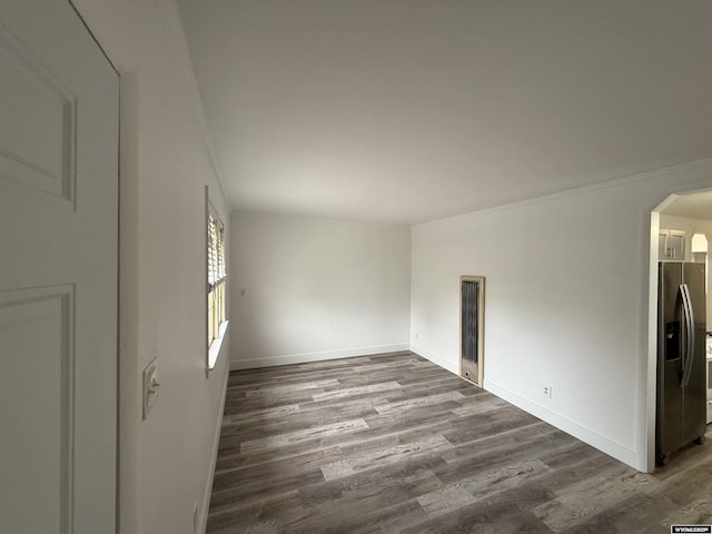 empty room featuring crown molding and dark wood-type flooring