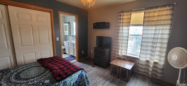 bedroom featuring connected bathroom, wood-type flooring, sink, and a chandelier