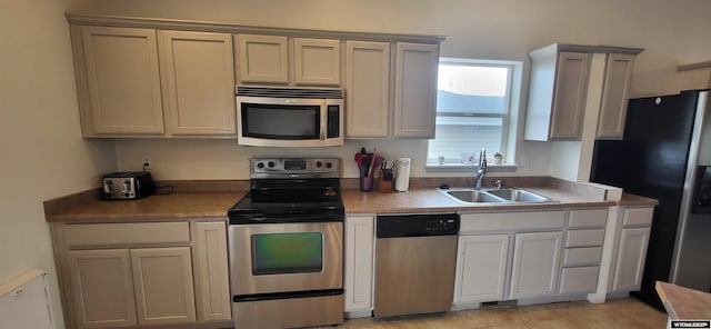 kitchen featuring stainless steel appliances, sink, and light tile patterned floors