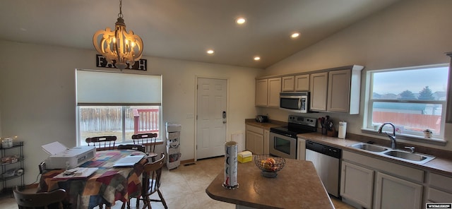 kitchen featuring lofted ceiling, sink, gray cabinets, hanging light fixtures, and stainless steel appliances