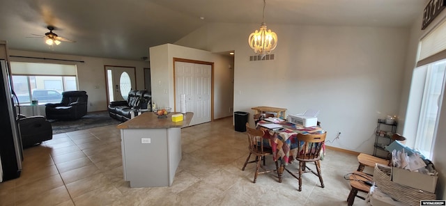 kitchen with lofted ceiling, light tile patterned floors, stainless steel fridge, a notable chandelier, and pendant lighting