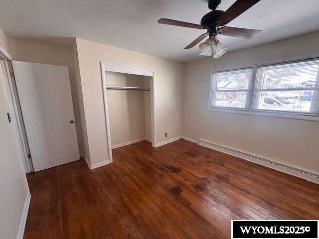 unfurnished bedroom with dark hardwood / wood-style floors, ceiling fan, and a closet