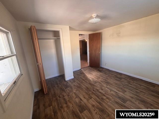 unfurnished bedroom with dark wood-type flooring and a closet